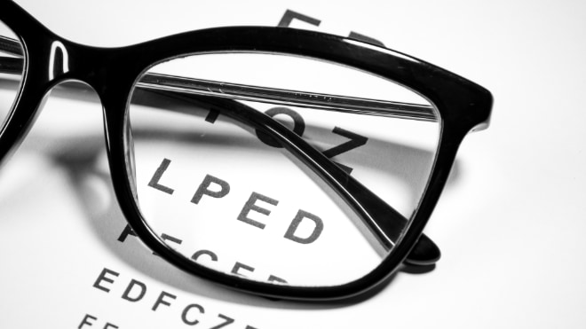 A pair of glasses rests on an eye test chart.