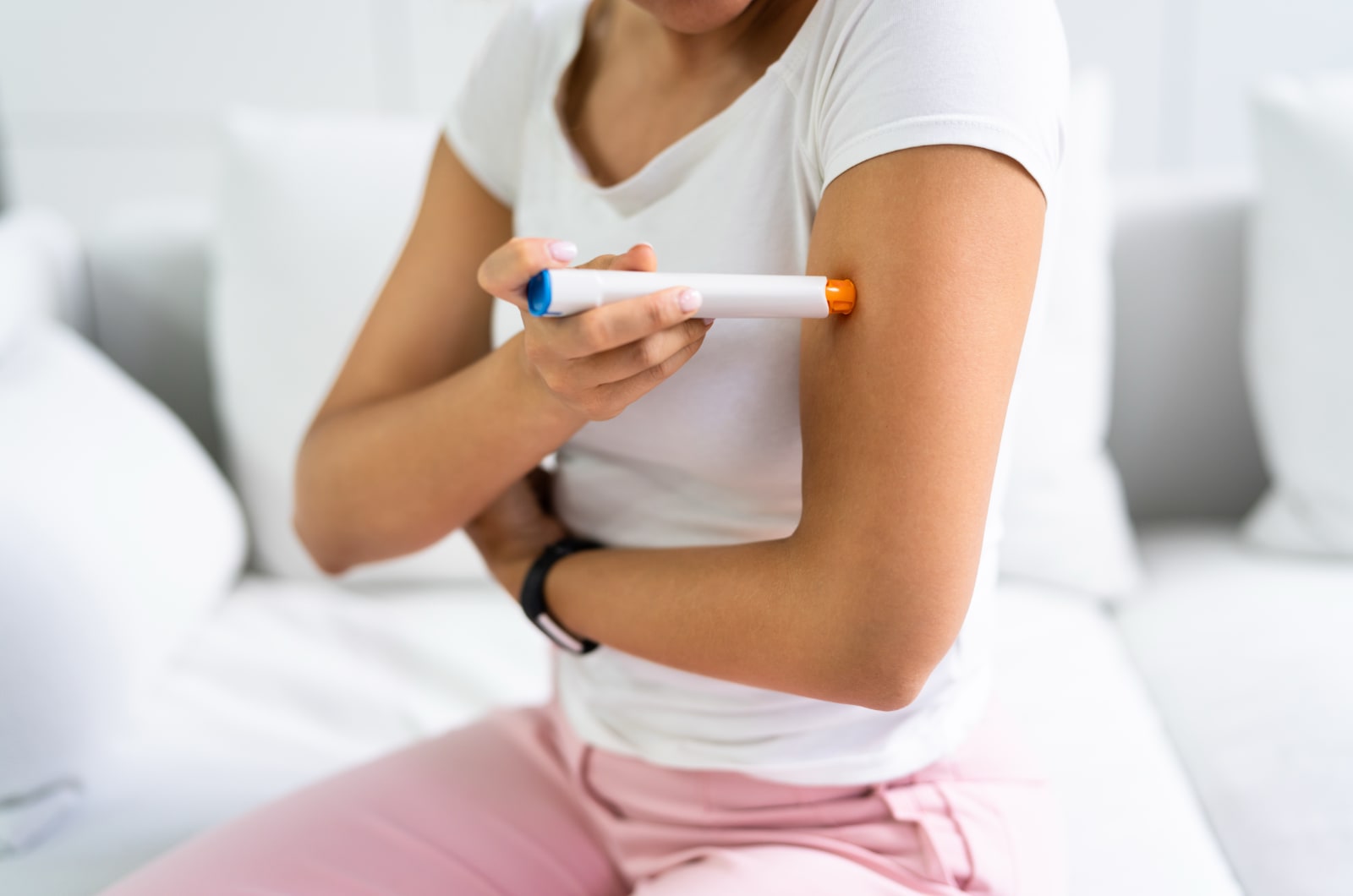 A user of a insulin auto-injector holding it up to their arm.