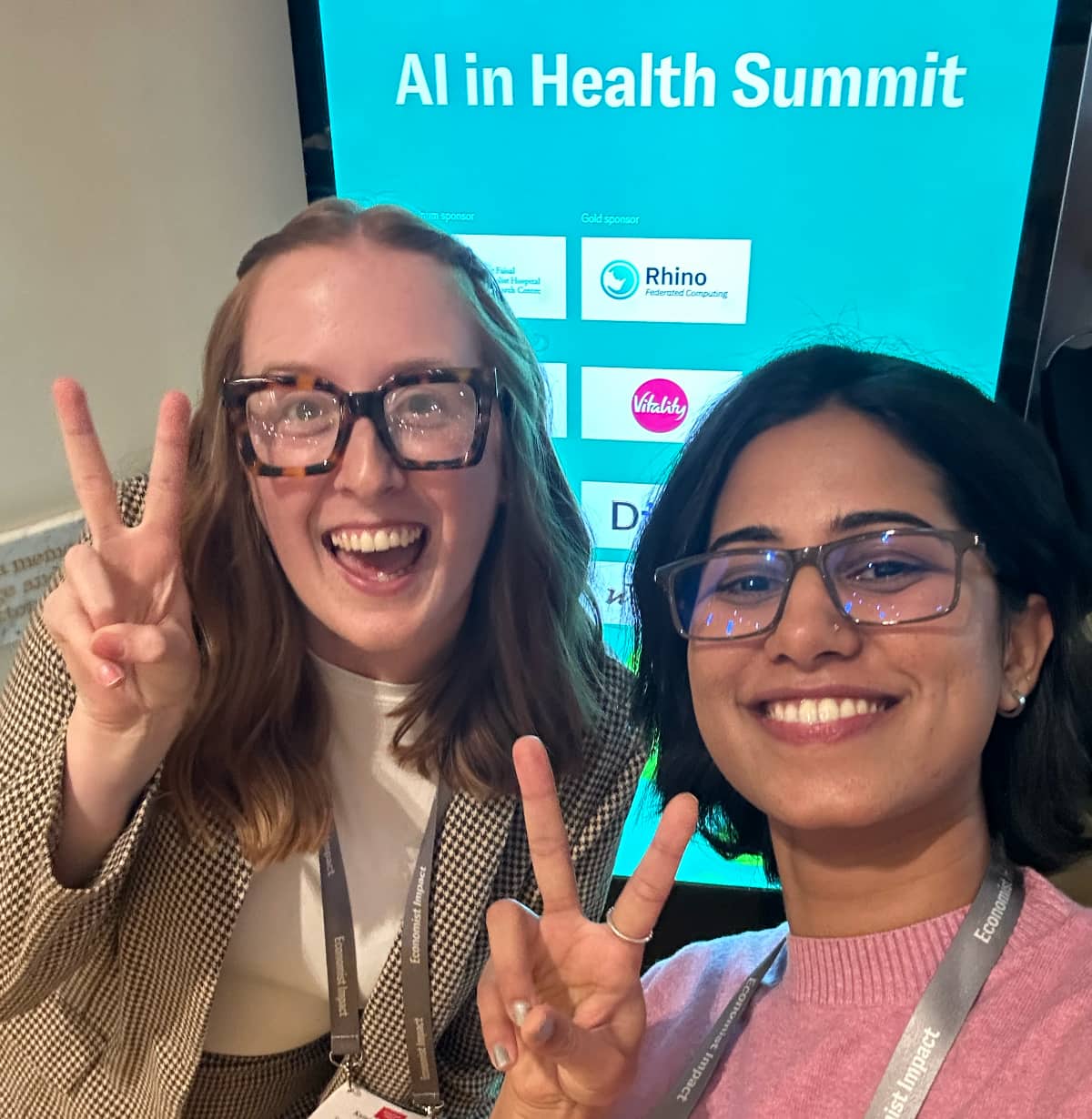 Kamiya and Sandra posing infront of a banner at the AI Health Summit.