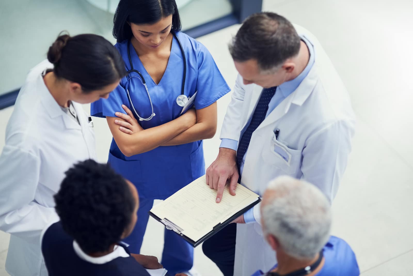 A team of doctors looks over notes on a clipboard.