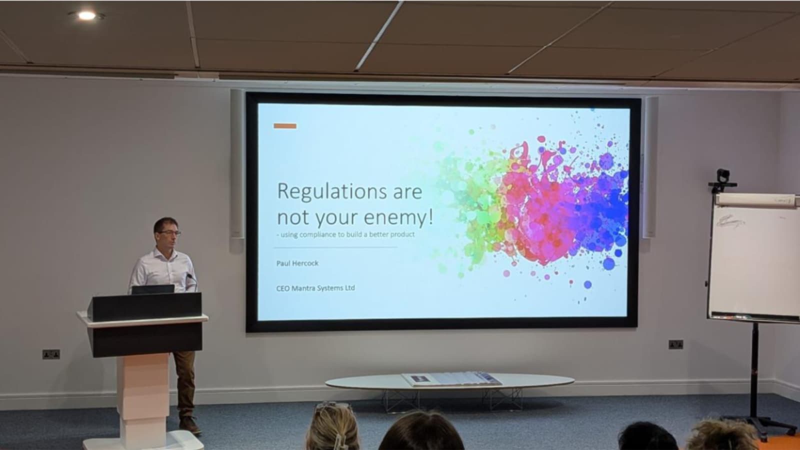 Paul standing behind a lecturn with the slide 'Regulations are not your enemy!