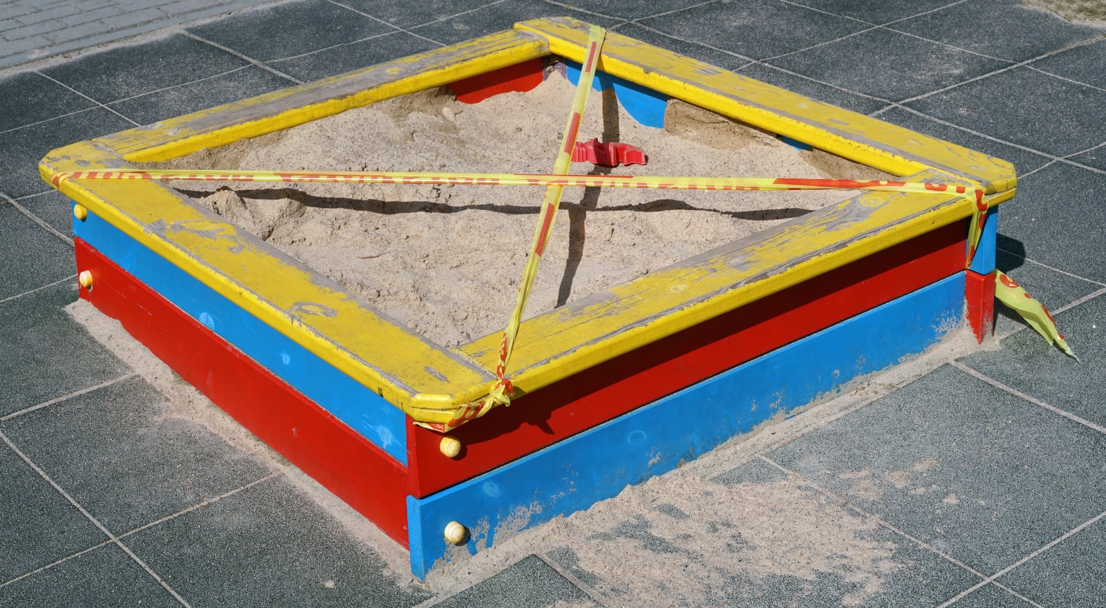 A childrens sandpit, closed using safety warning tape.