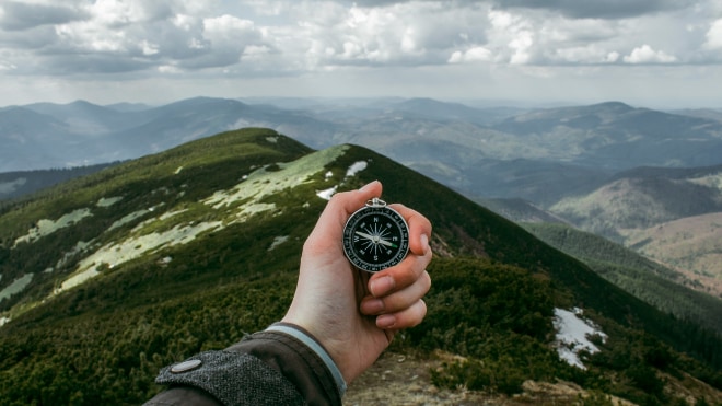 A compass being used to navigate across mountainous countryside.