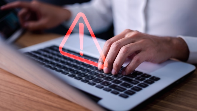 A laptop projects an alert to a user sitting at a desk.